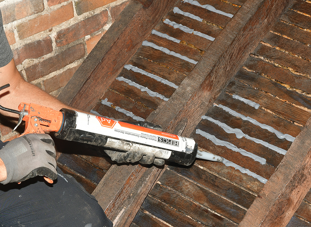 The final stage of consolidation: Applying AD Premixed key replacement adhesive to the cleaned and consolidated plaster.